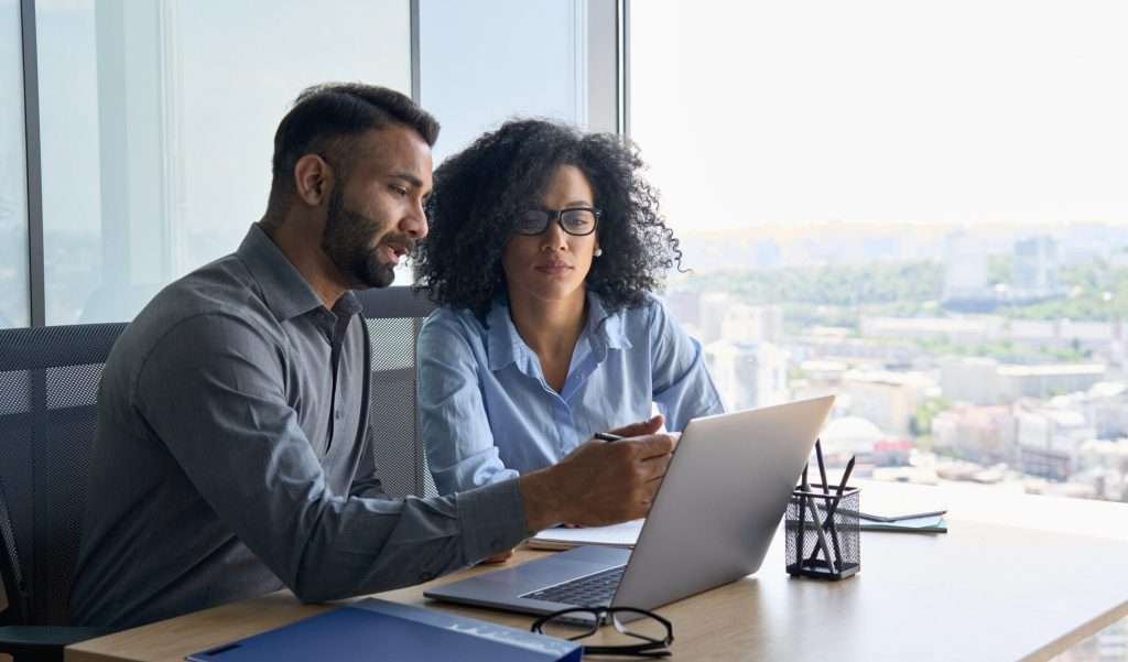two people in the workforce looking at a laptop