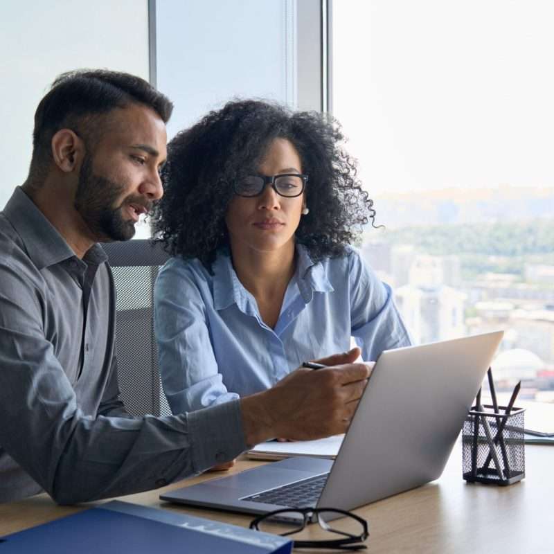 two people in the workforce looking at a laptop