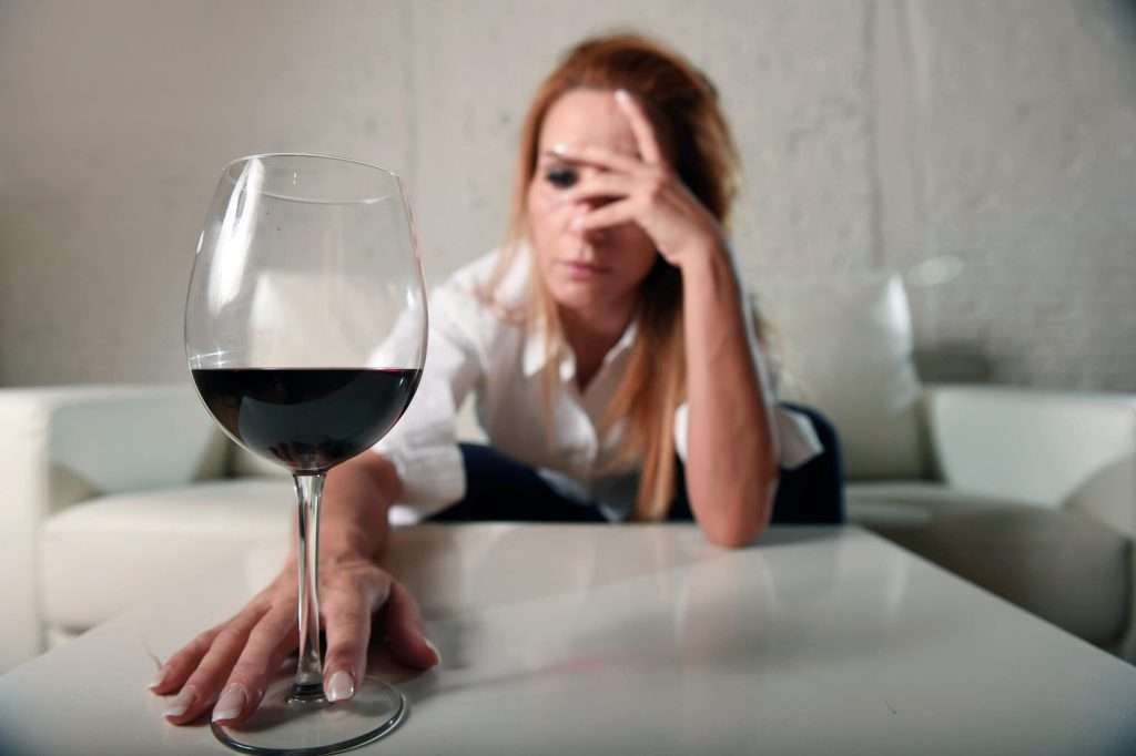 a woman with a glass of wine contemplating if she has an alcohol use issue
