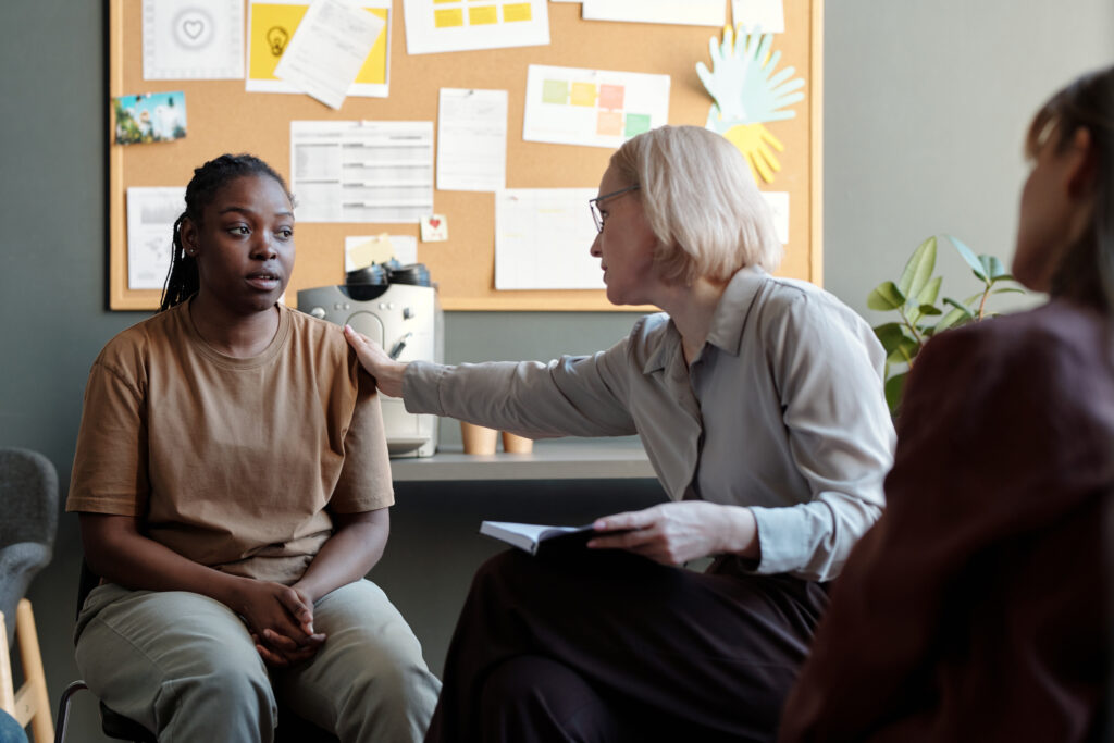 A therapist putting a comforting hand on a young woman's shoulder who is the beneficiary of the Florida Baker Act.
