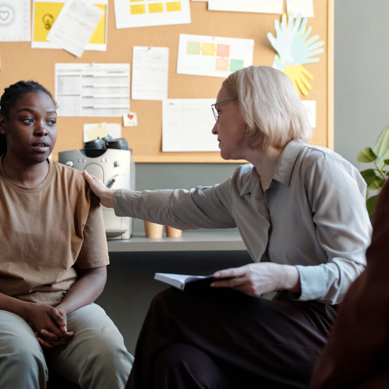 A therapist putting a comforting hand on a young woman's shoulder who is the beneficiary of the Florida Baker Act.