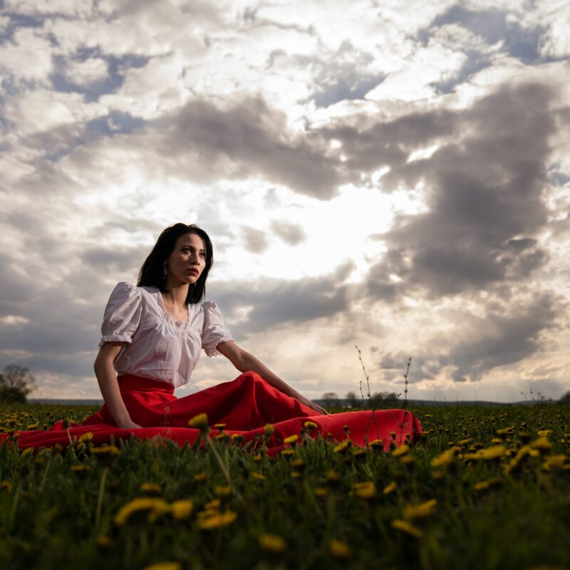 A young woman sitting in a field under the clouds looking for the best rehabs in Florida