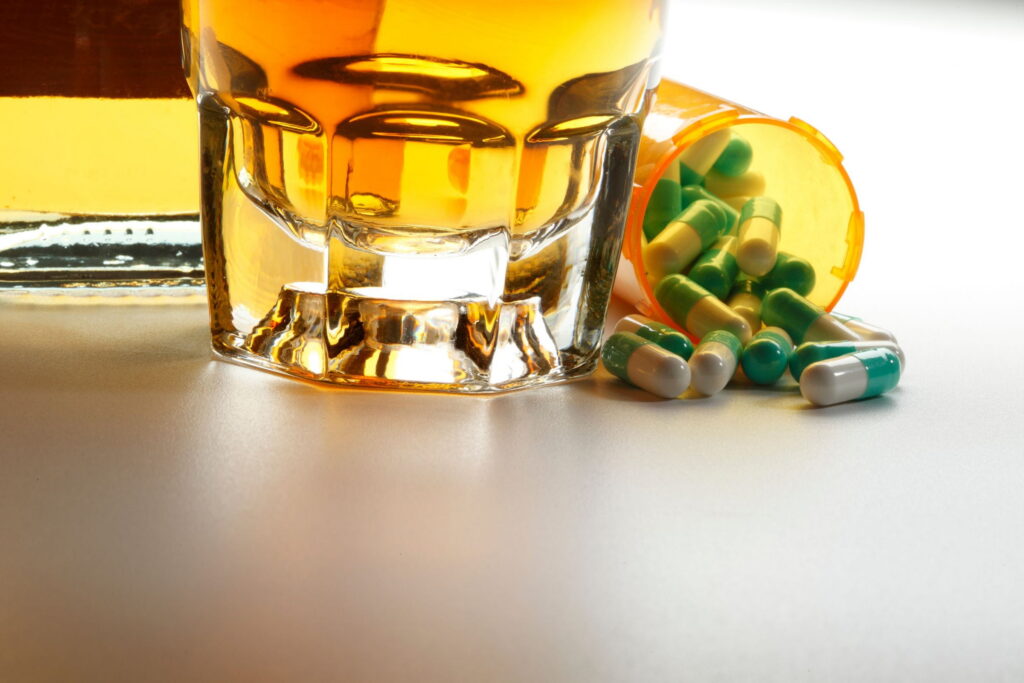 glass of alcohol with Lexapro capsules
